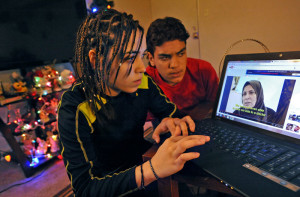 Baltimore, MD-4/8/15 - Reema Alfaheed, left, at home with her younger brother, Ahmed Alfaheed, 15, look at videos depicting the Iraq refugee camp near the border with Jordan, where they lived for six years after fleeing Baghdad. Amy Davis/Baltimore Sun Staff Photographer - #2383